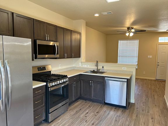 Partial view of kitchen and partial view of living room with new ceiling fan and window facing outside front of duplex.