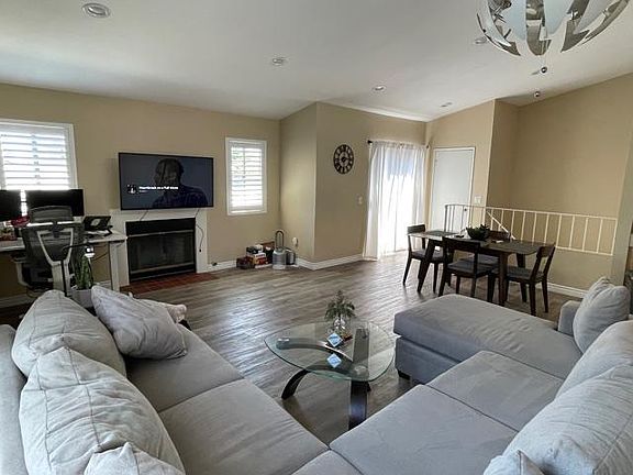 Spacious living room furnished with dining table, couch, coffee table, and TV