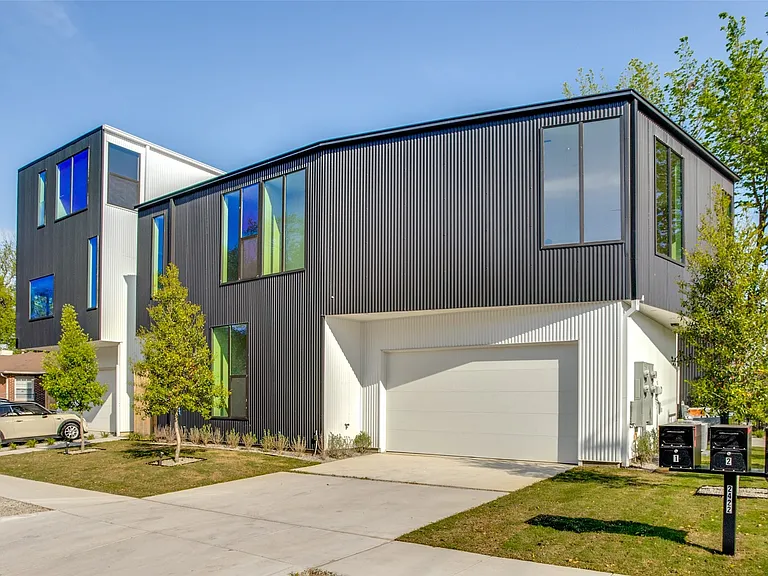 Contemporary architectural facade featuring dark corrugated metal siding and white vertical paneling