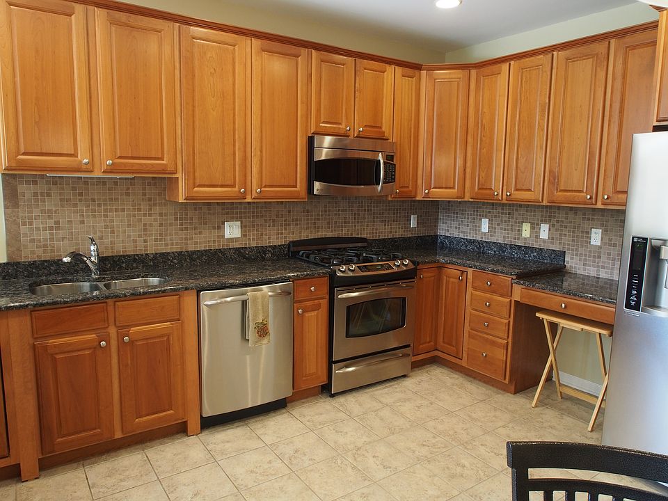 large kitchen with stainless steel appliances, modern tile and under lighting below cabinets