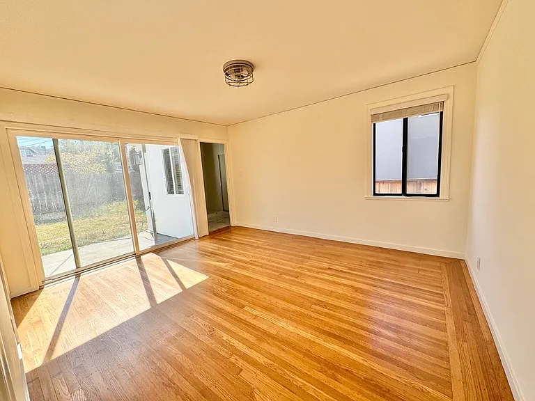Spacious primary bedroom with attached bathroom and access to backyard patio.