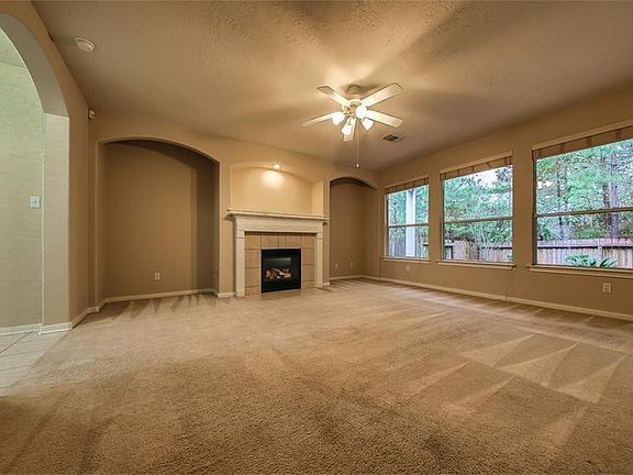 Another view of the large den with a wall of windows and a ceiling fan.