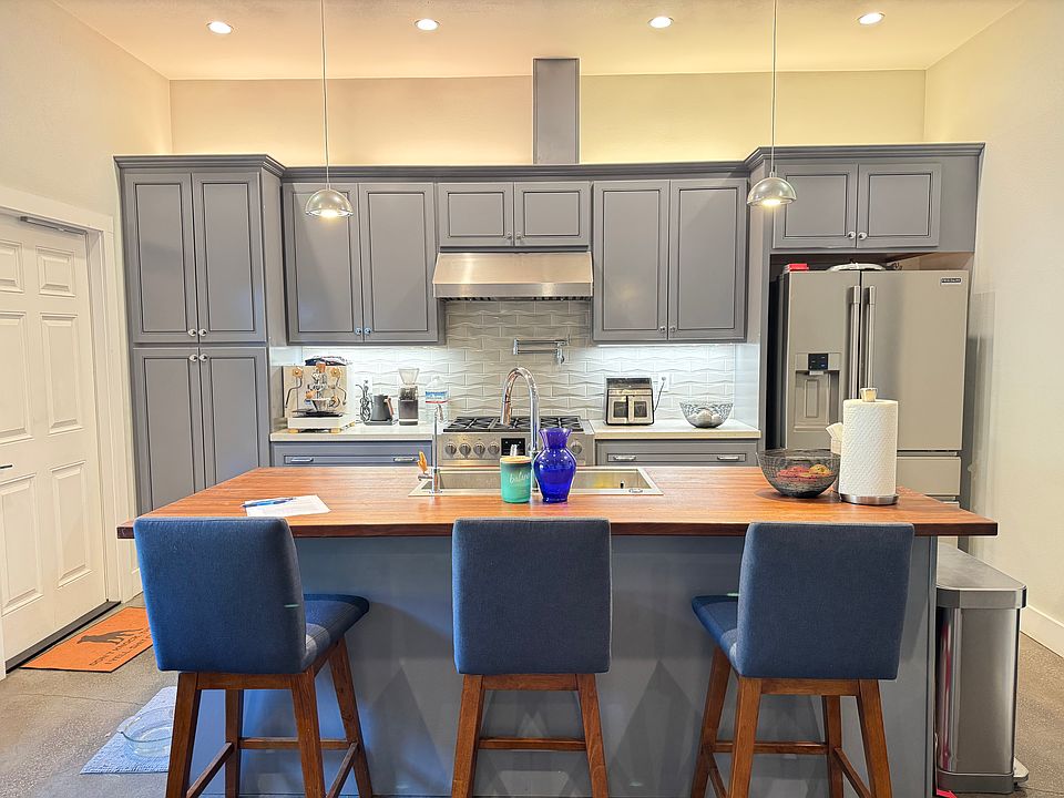 Kitchen with wide aisleway. Stainless appliances, 36" gas range/oven, powerful exhaust fan, tile backsplash, pot filler, quartz countertops. Center island has dishwasher, deep basin sink, walnut butcher block, and room for seating.