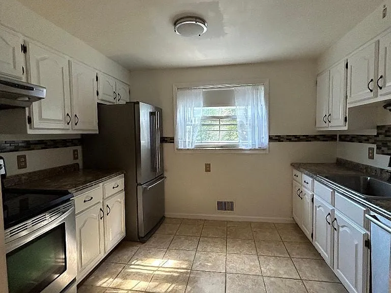 Full view of the kitchen with tile floors, large window, stainless appliances, modern feel.