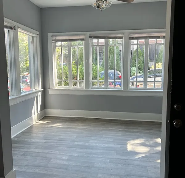 A glowing sunroom with floor-to-ceiling windows, offering a bright, versatile space ideal for meditation, reading, an office, or a cozy den.