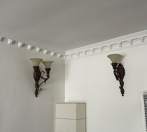 Living room crown molding, with wonderful wall sconces. The walls and ceiling are painted white, giving a beautiful light and e