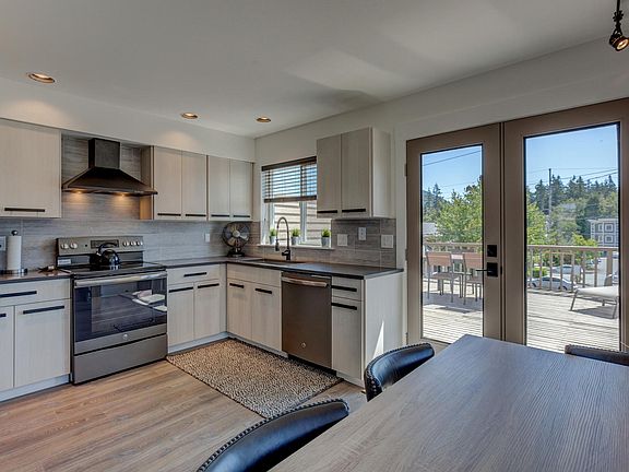 Large kitchen with laminate flooring, stainless steel appliances and upper deck