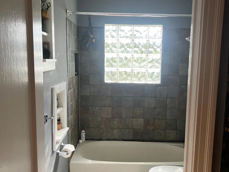 Full bathroom with glass block window in the shower.