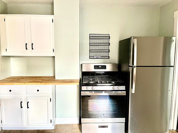 Kitchen with new butcher block cabinets and stainless steel appliances.