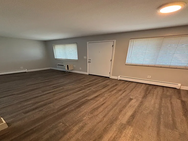 Inviting living area featuring elegant wood flooring, large windows, and modern lighting.