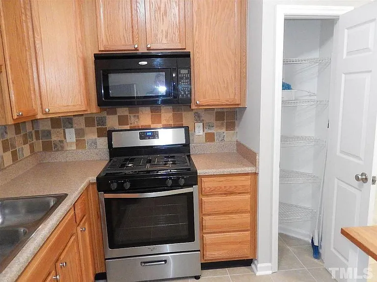 Gas Stove & Storage Pantry. Tile backsplash.