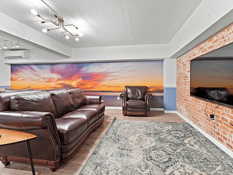 Experience relaxation in this inviting living room, featuring elegant leather furniture and a stunning sunset backdrop.