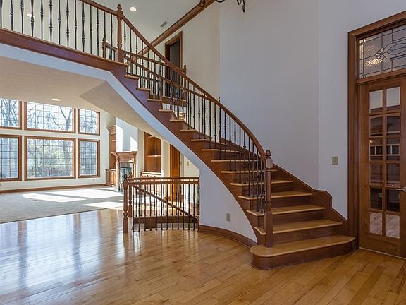 Soaring entry with curved staircases, wrought iron railing and gleaming hardwood floors