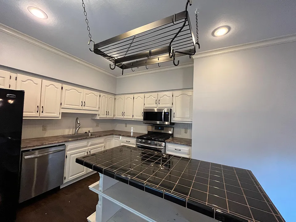 Kitchen view displaying stainless steal and black appliance, and plenty of cabinets space