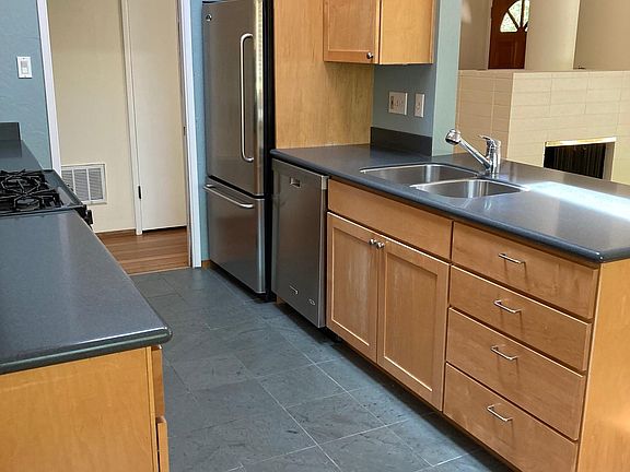 Remodelled kitchen with opening skylight, slate floors, Corian countgertops, hardwood cabinets, gas stove. Concrete block fireplace.