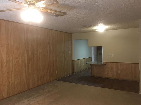 Living room with ceiling fan looking toward bar and kitchen.