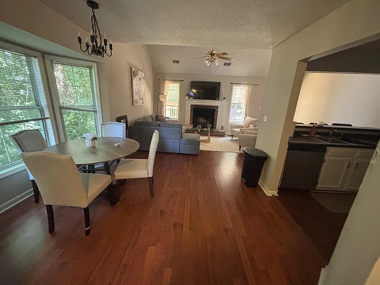 Open-concept living and dining area with hardwood floors, a fireplace focal point, and large windows for natural light.