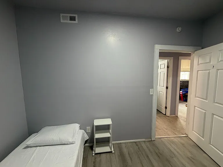 Private bedroom with gray walls, durable flooring, and space for a bed and nightstand, with easy access to the hallway.