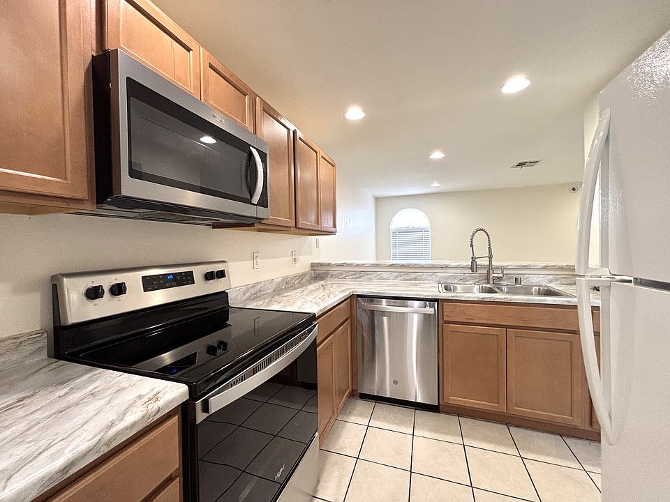 Large open modern kitchen with stainless steel appliances & sink, tiled floor, recessed LED lighting with dimmers, wood cabinets...