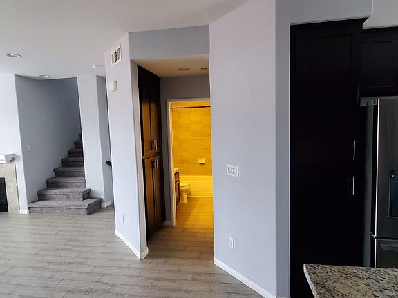 Living room with a view of the staircase, fireplace, bath in the second level, and a peek at the kitchen.