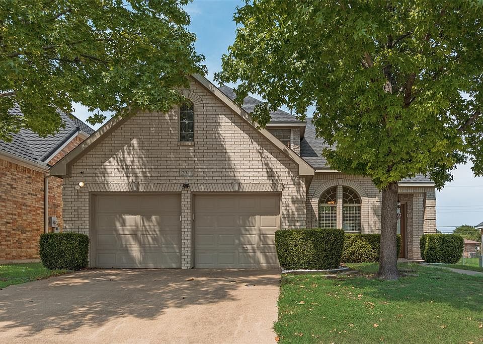 View of front facade with driveway, brick siding, an attached garage, and roof with shingles