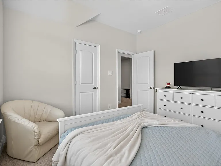 Well-lit interior space featuring light neutral wall paint, white trim, a white paneled door, and carpet flooring