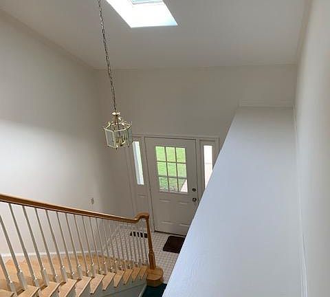 View from balcony on second floor looking down to entry way. Lots of light with one of 2 skylights.