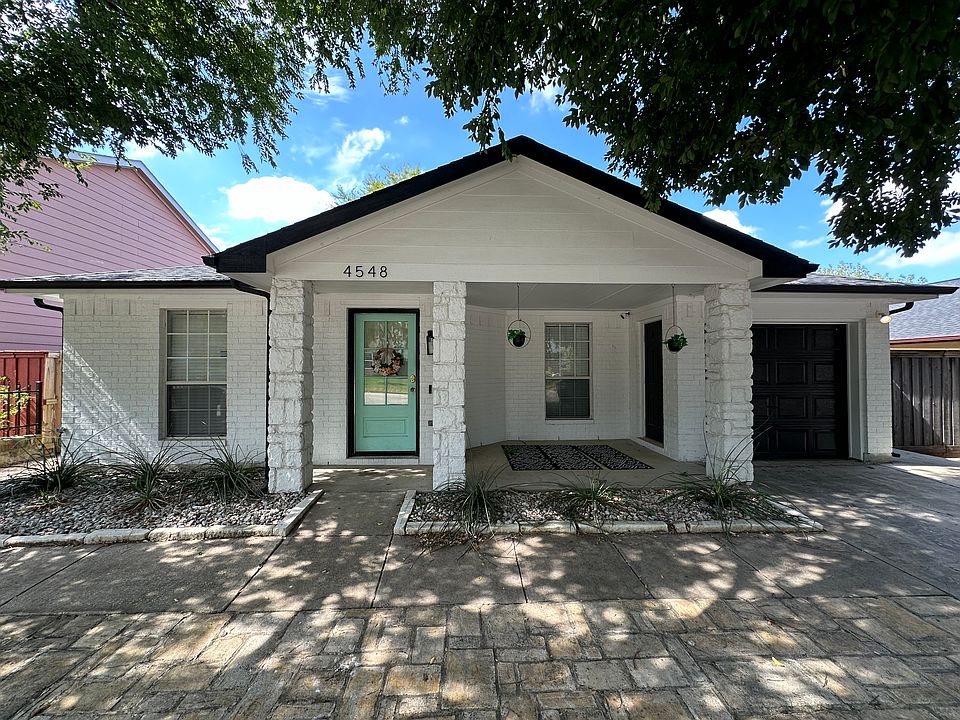 View of the front of property with a covered front porch for a nice sitting area and a 1-car garage. Two mature trees provide plenty of shade and a small garden with succulents for minimal maintenance.
