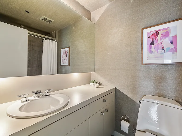 Full bath featuring an expansive vanity, oversized mirror, and textured walls.