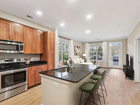 Updated Finishes kitchen with stainless steel appliances, grey tile backsplash, granite countertops, and new hard surface flooring and lighting