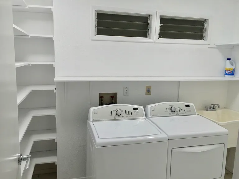 Washer/dryer room with ample shelving and storage space.