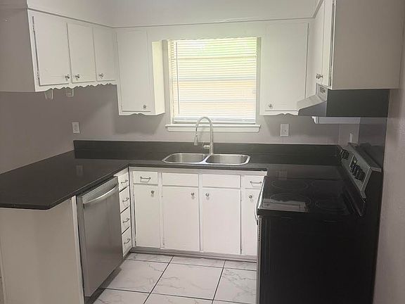 Kitchen with granite countertops & stainless & black appliances.