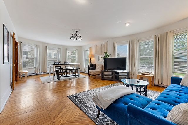 Spacious living room with comfortable sofa, working desk and large table.