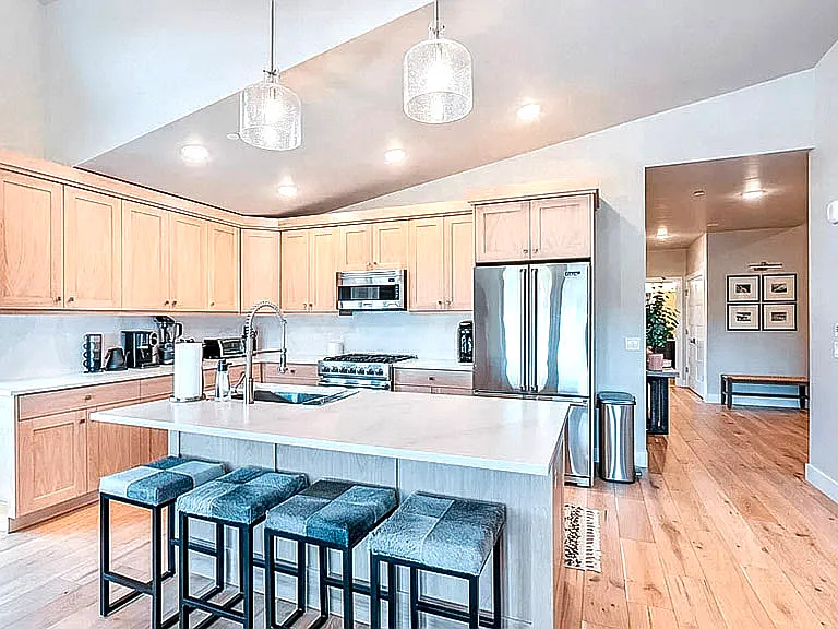Gourmet kitchen with large island, stainless steel French door refrigerator, gas range, and open sightlines to the living area