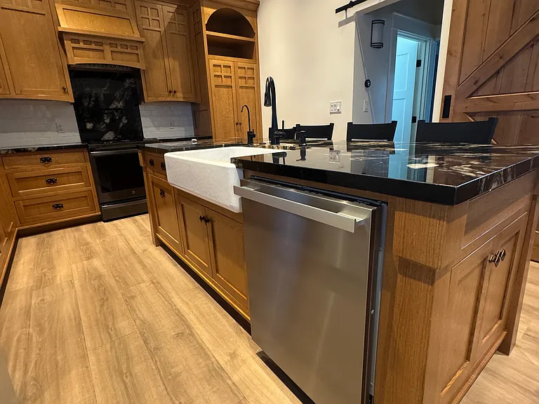 Kitchen with Miele dishwasher and farmhouse sink in the granite covered island
