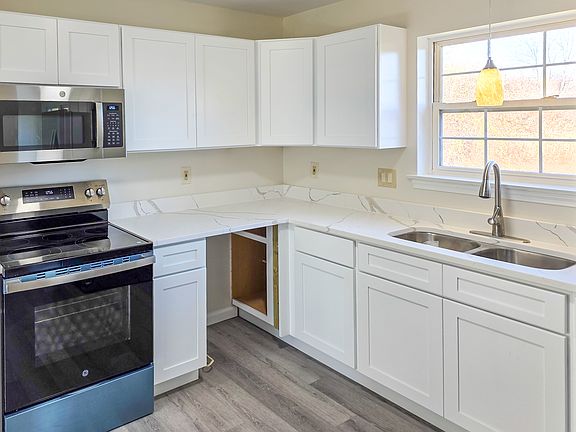 Main Floor -Remodeled Kitchen - Crisp white cabinetry, sleek white quartz countertops, SS Appliances, Fridge, Electric stove, Dishwasher, Microwave, pendant light over sink