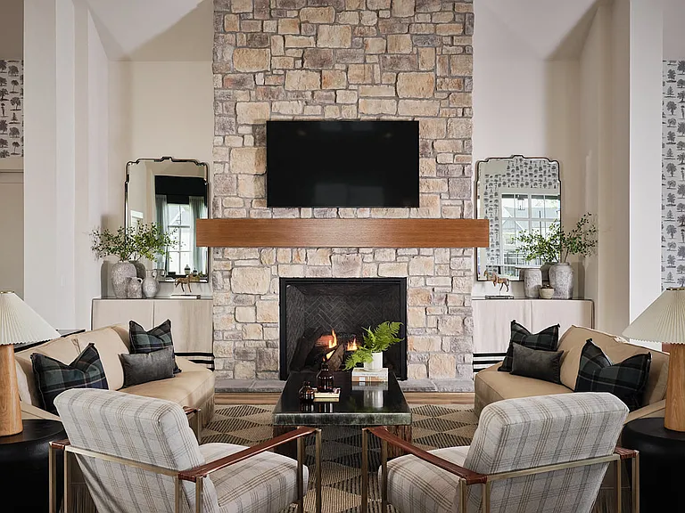 Inviting clubhouse living room featuring cozy seating, a fireplace, and a large TV for entertainment.
