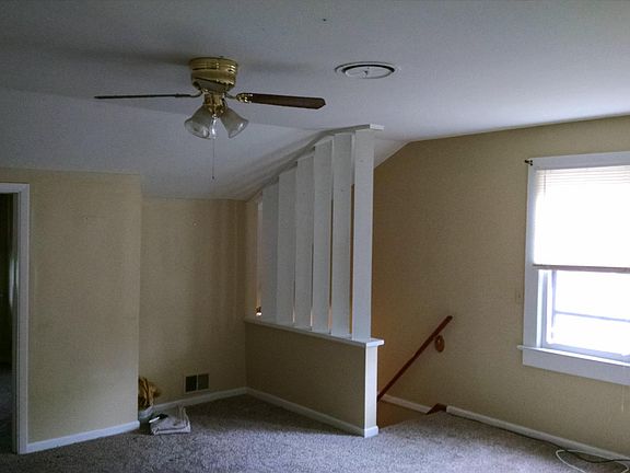 View from kitchen area, back across living room towards stairs, entry to the front bedroom is on the left
