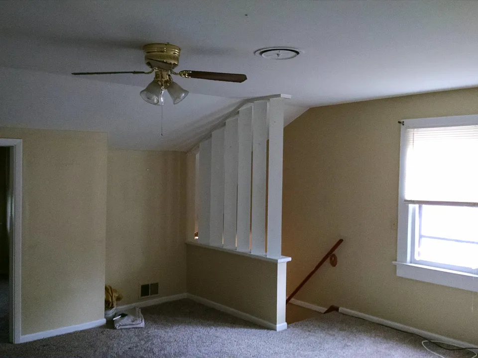 View from kitchen area, back across living room towards stairs, entry to the front bedroom is on the left