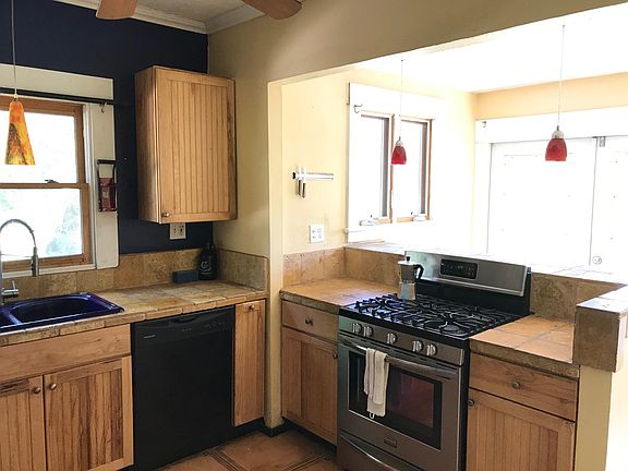 Kitchen w/ Maple Cabinets, Travertine Counters, Cast Iron Sink, and Gas Range; Modern Double-Hung Window with Screen
(Photo facing southwest towards breakfast bar)