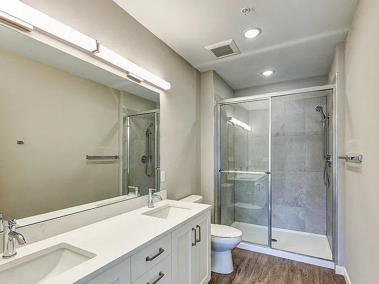 Imperial Crossing Luxury Apartment Homes unit showing a bathroom with dual sinks and walk-in shower.
