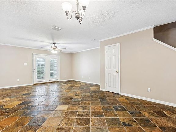 Spare room featuring dark tile patterned flooring, ceiling fan with notable chandelier, a textured ceiling, and ornamental molding