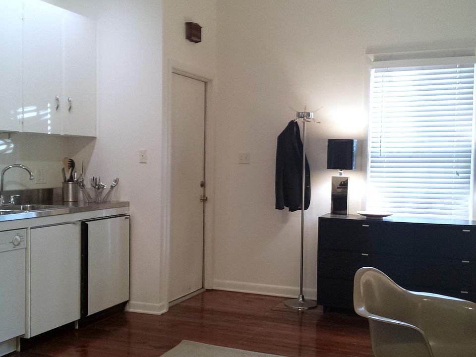 ENTRANCE DOOR INTO LIVING ROOM WITH GALLEY KITCHEN, WINDOW OPENS TO THE LANE.