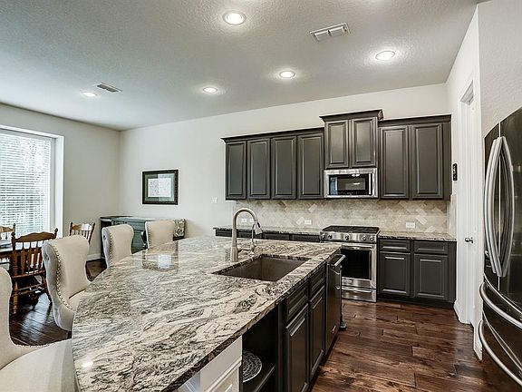 The Kitchen features exotic granite, charcoal cabinets, planked hardwood floors, stainless steel appliances and enormous walk in pantry.