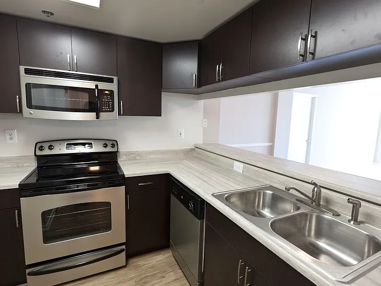 Classic Package II kitchen with grey countertops, espresso cabinetry, stainless-steel appliances, and hard surface flooring (select homes)