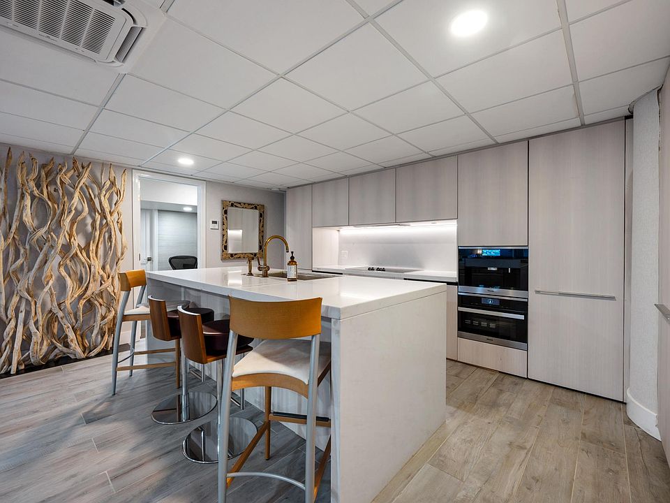 Kitchen, equipped with dishwasher, stove, oven, hood fan, fridge, freezer, bar, cabinets, cookware, cutlery, and glasses.