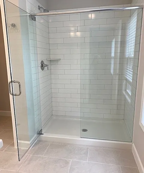 Primary bathroom shower with seamless glass door.