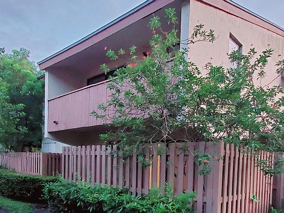 View of unit from front, private fenced patio and upstairs master bedroom balcony.