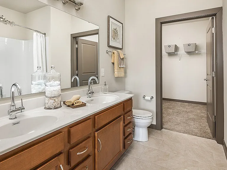 Spacious bathroom with dual vanities, a tub-shower combo, and a walk-in closet_everything you need in one place at our Fishers apartments.