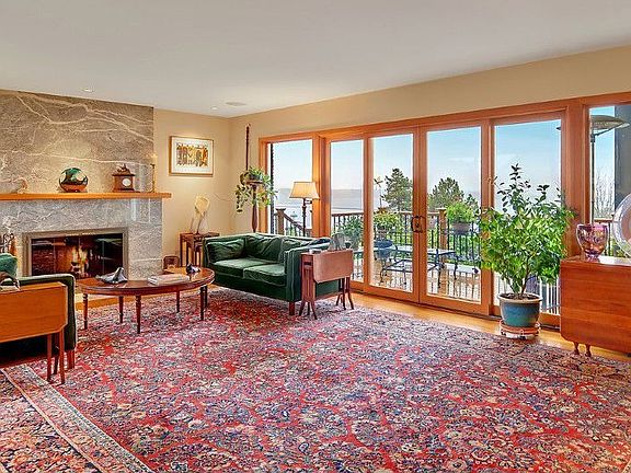 Elegant living room provides a formal yet comfortable atmosphere for relaxing or entertaining and is graced with a wall of windows to showcase the panoramic lake and mountain views and bring the outdoors in. Enjoy sitting by the slab marble fireplace, conversing with friends, or curling up with a good book on a blustery night. There is a sound system in nearly every room. The floor plan lends itself well to entertaining, whether for large groups or more intimate gatherings, indoors or out.